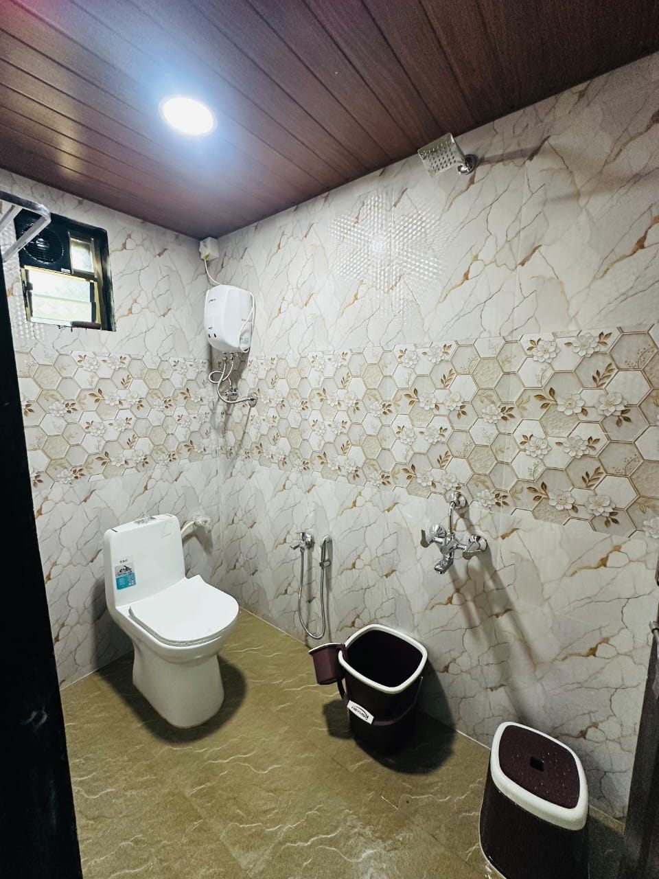 Marble-tiled bathroom with western toilet and shower