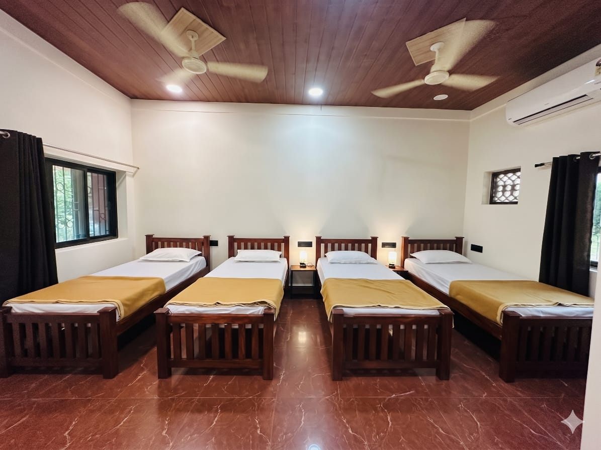 Large room with four wooden single beds, AC and ceiling fans