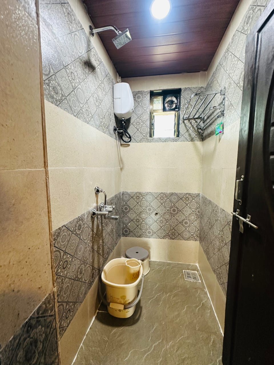 Tiled shower room with geyser and towel rack