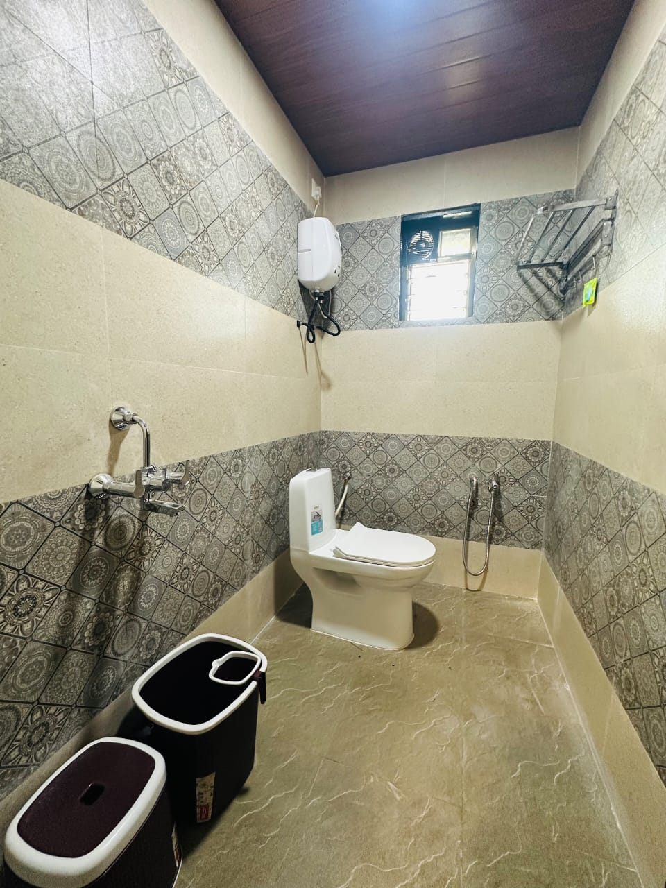 Tiled bathroom with western toilet, shower and geyser