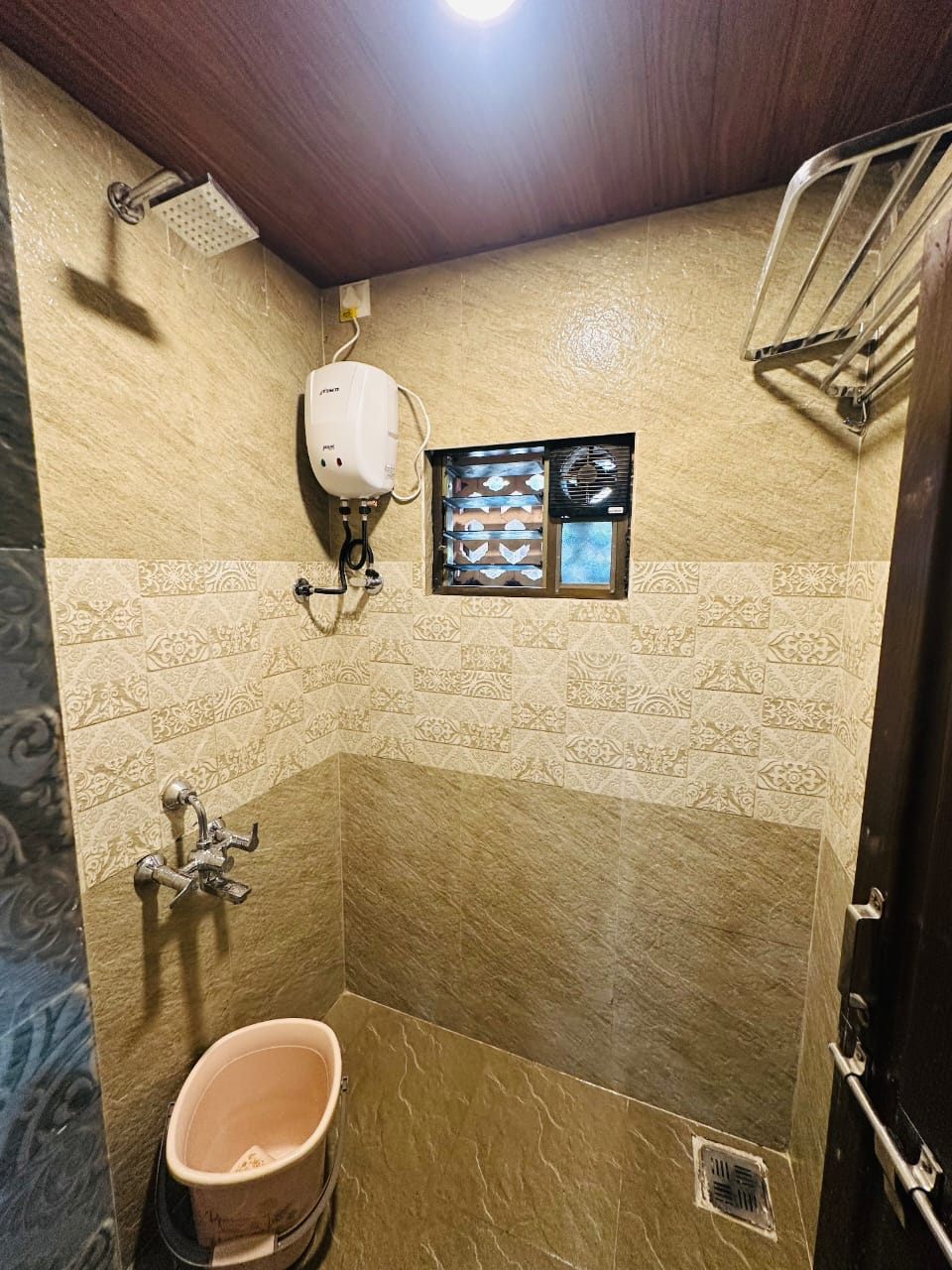 Tiled shower room with geyser and towel rack